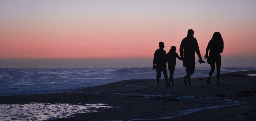 Family walking on a beach during the sunset protected with life insurance.